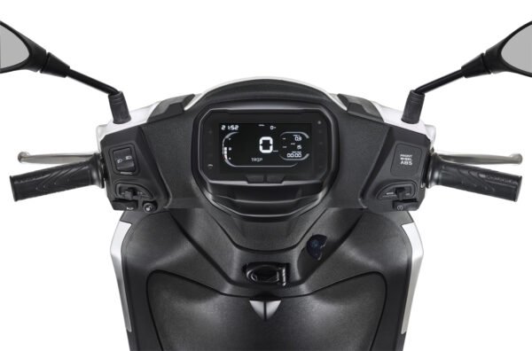 Close-up view of a motorcycle dashboard featuring a digital display with speed and trip information, two handlebar grips, and control buttons for various functions on either side.