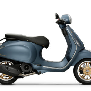 The Vespa Primavera 125 Officina 8 Euro 5+ A blue Vespa scooter with a rounded design and gold accents, viewed from the side, showcasing its seat, handlebars, and wheels.