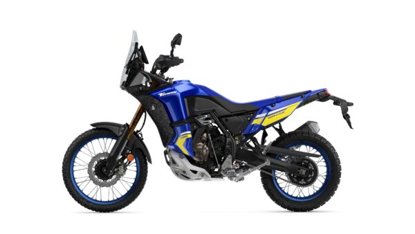 A blue and black adventure motorcycle with yellow accents, featuring off-road tires, a tall windshield, and a rugged design, positioned against a white background.