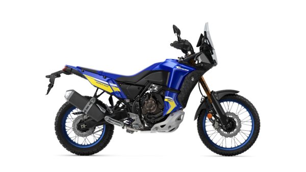 A blue and yellow adventure motorcycle is displayed on a white background, showcasing its rugged design, off-road tires, and prominent features including a front windscreen and dual-exhaust system.