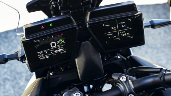 Close-up of a motorcycle's digital dashboard displaying speed (0 km/h), trip distance (2.5 km), temperature (Lo °C), and fuel consumption metrics.