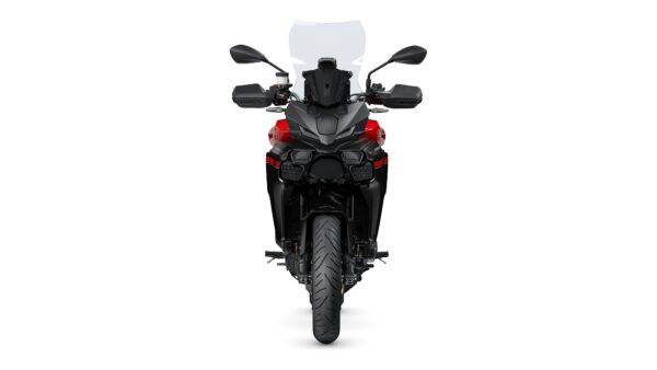 A modern motorcycle with a sleek black and red design, featuring a tall windshield, dual headlights, and a robust front tire, viewed head-on against a white background.