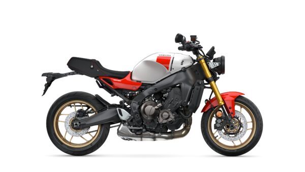 A side view of a modern Yamaha XSR900 motorcycle, featuring a sleek design with a silver and red color scheme, gold alloy wheels, and a powerful engine.