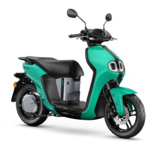 Yamaha 2023 Neos A turquoise electric scooter with a modern design, featuring a black seat and dual headlights, positioned at an angle to showcase its sleek body and front wheel.