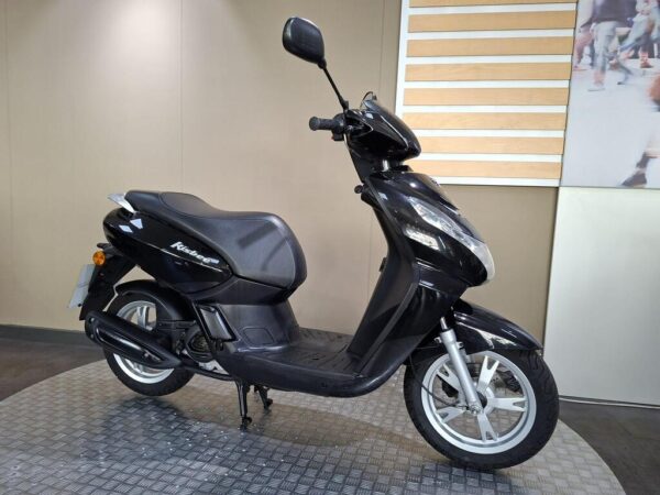 A black scooter is displayed on a textured floor against a neutral background, showcasing its design and features.