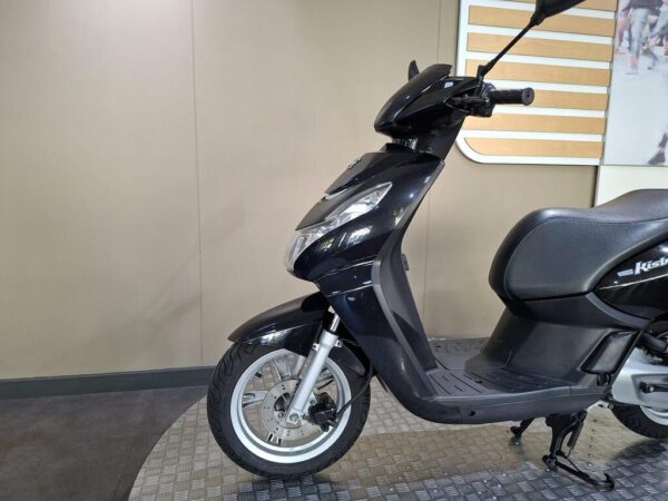 A black scooter parked on a textured floor, showcasing the front wheel, handlebar, and side profile against a neutral background.