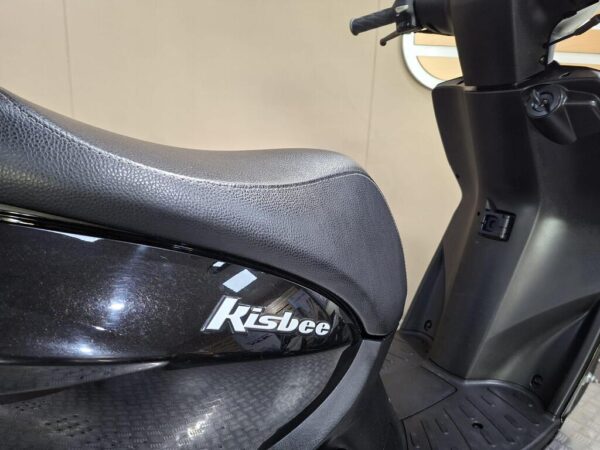 Close-up of a black scooter seat with the brand name "Kisbee" visible, against a neutral background.