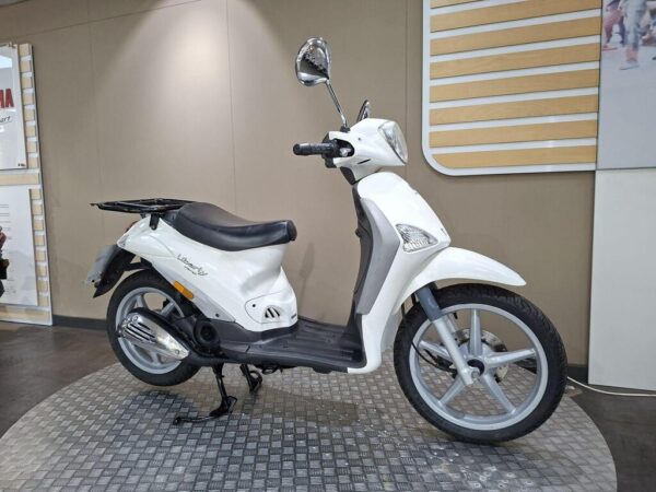 A white scooter displayed on a textured circular platform, featuring a black seat, mirror, and modern design elements, set against a neutral background.