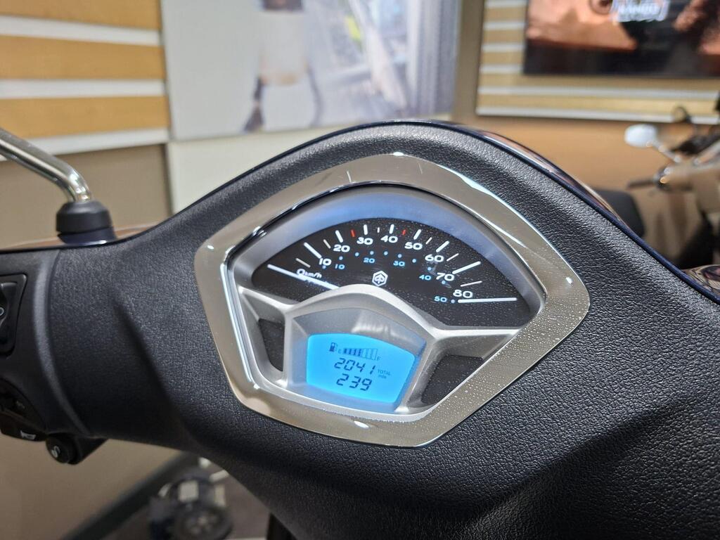 Piaggio Liberty 50 (2019) 9 Close-up of a scooter's dashboard displaying speedometer and odometer readings; speedometer indicates 0 km/h while the odometer shows 204.1 km. The background is blurry with some interior design elements visible.