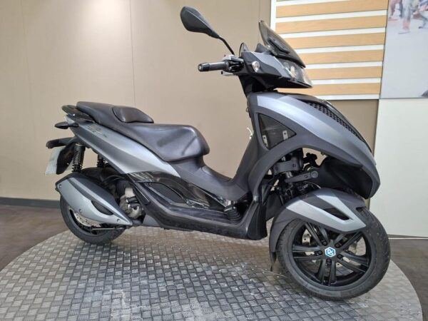 A sleek, modern scooter in a matte gray finish, featuring a streamlined body, dual front wheels, and a comfortable seat, displayed against a neutral background.