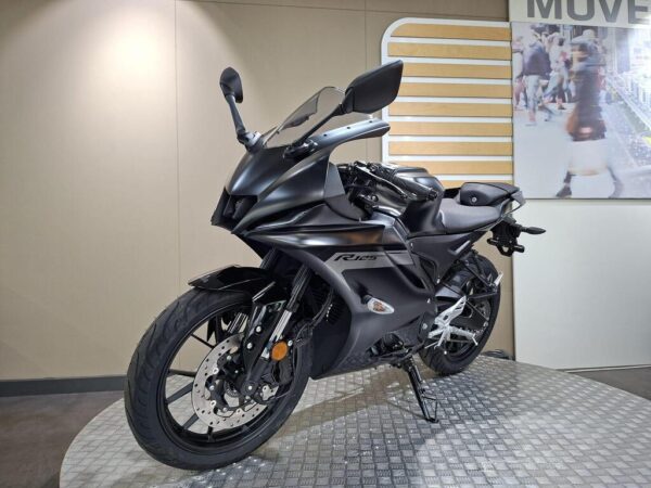 A sleek black motorcycle displayed on a circular platform, with modern features and a minimalist background.