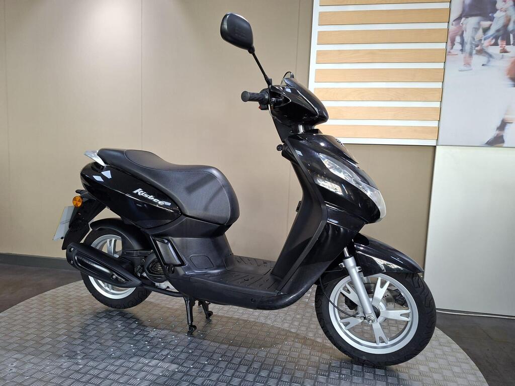 2018 Peugeot Kisbee LC18 NTK 2 A black scooter displayed on a circular textured platform, showcasing its side profile with a modern design, located in a well-lit indoor setting.