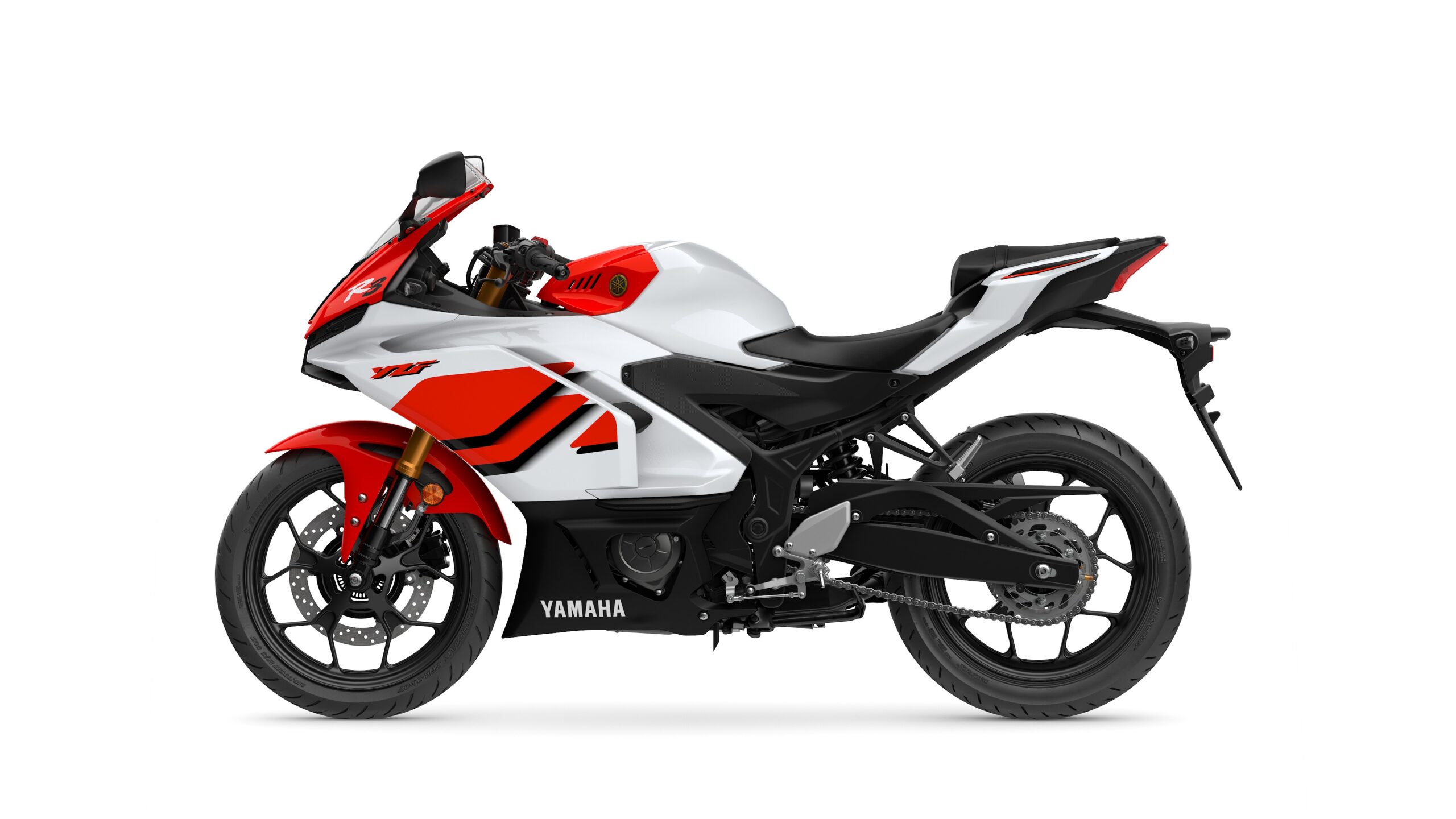 2026 Yamaha R3 Anniversary Edition Left A sleek, modern motorcycle with a predominantly white body, accented by red and black elements, shown from a side view. The bike features a sporty design, with prominent wheel rims, a prominent front fairing, and a streamlined seat.