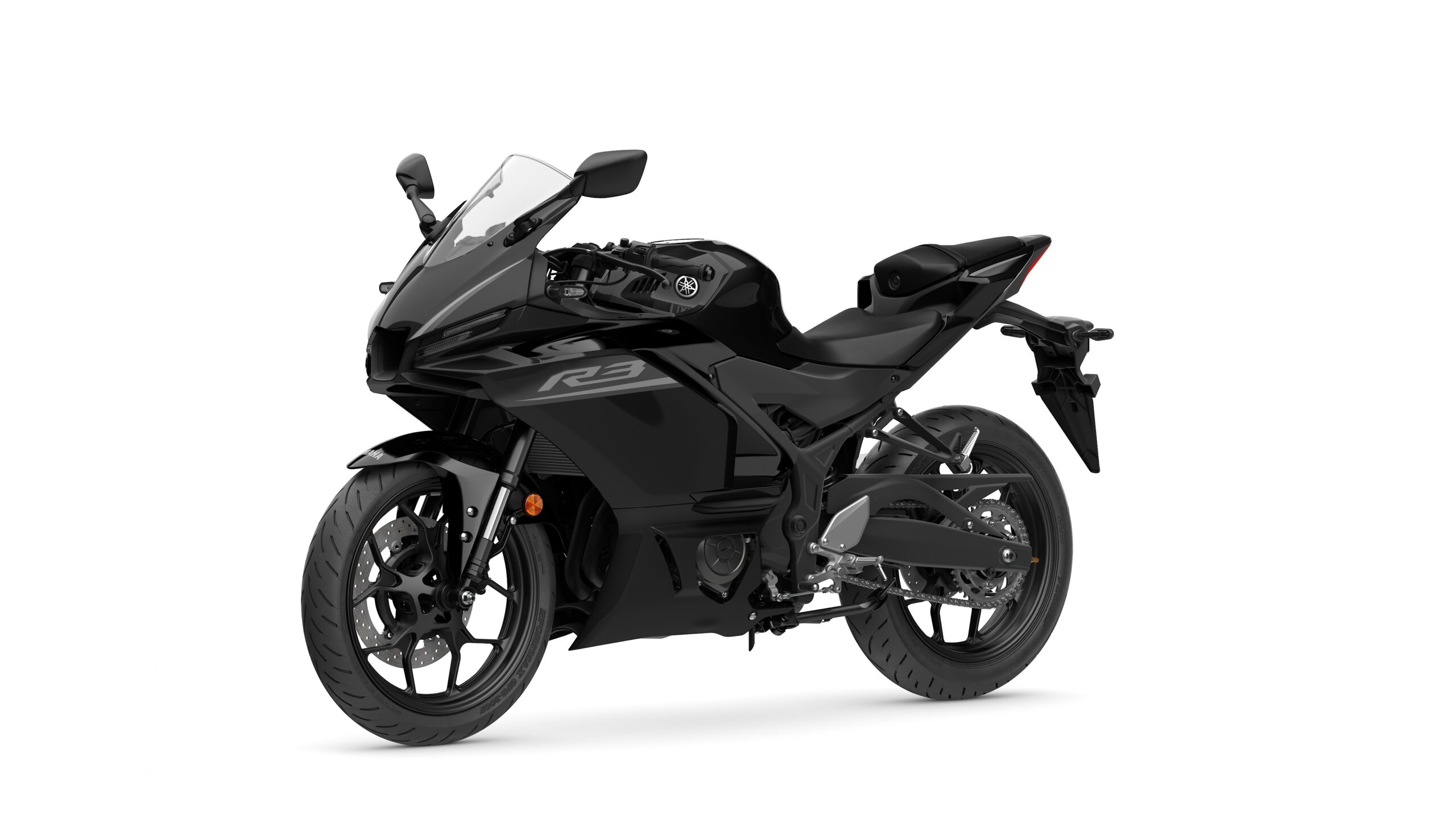 2026 Yamaha R3 Tech Black Lateral Left A sleek black sport motorcycle, model Yamaha R3, positioned at a slight angle showcasing its aerodynamic design, front fairing, and distinctive features.