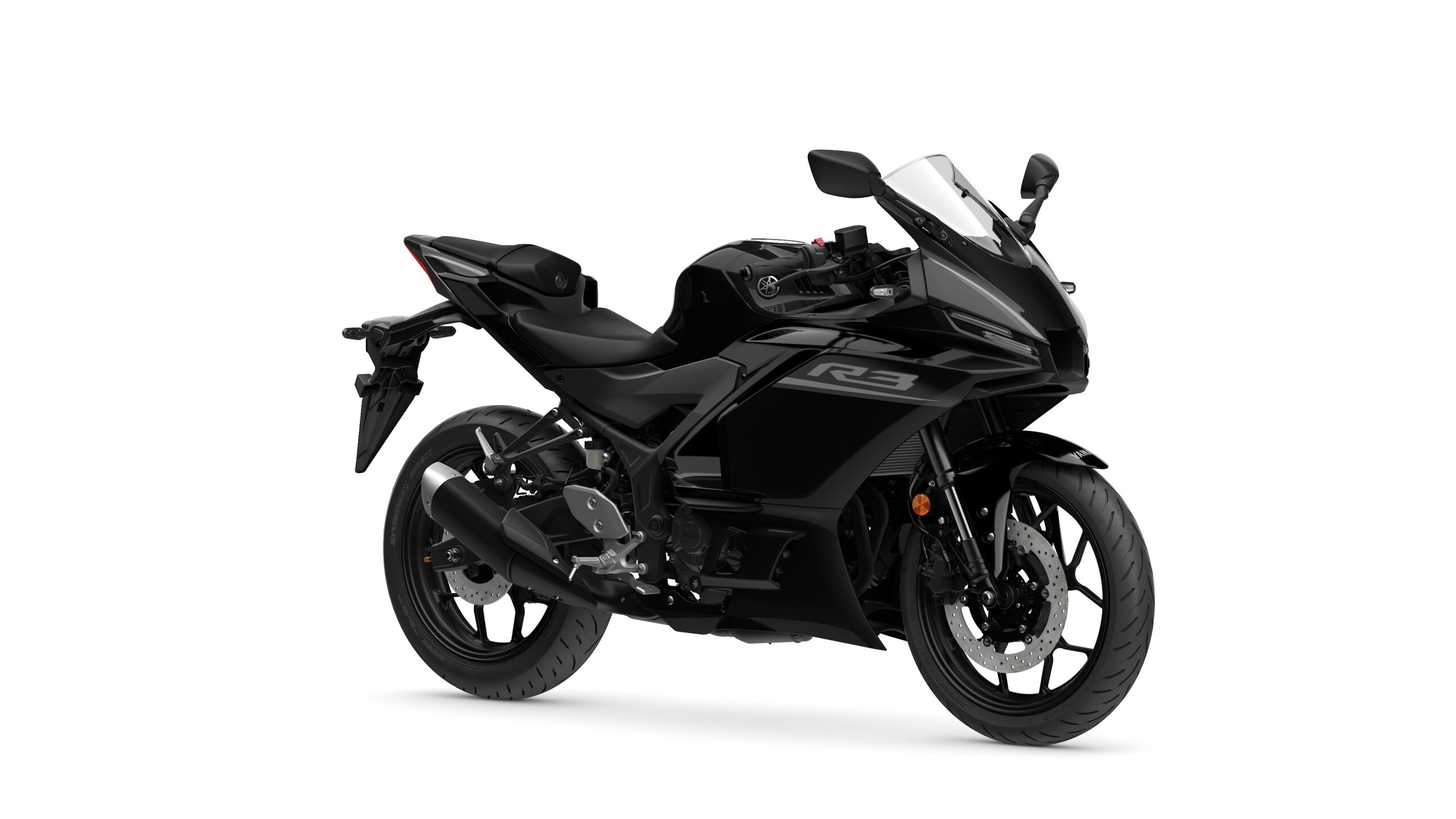 2026 Yamaha R3 Tech Black Lateral Right Yamaha 2026 R3 A sleek black Yamaha R3 motorcycle positioned at a slight angle, showcasing its aerodynamic body, sport seat, and dual headlights against a plain white background.