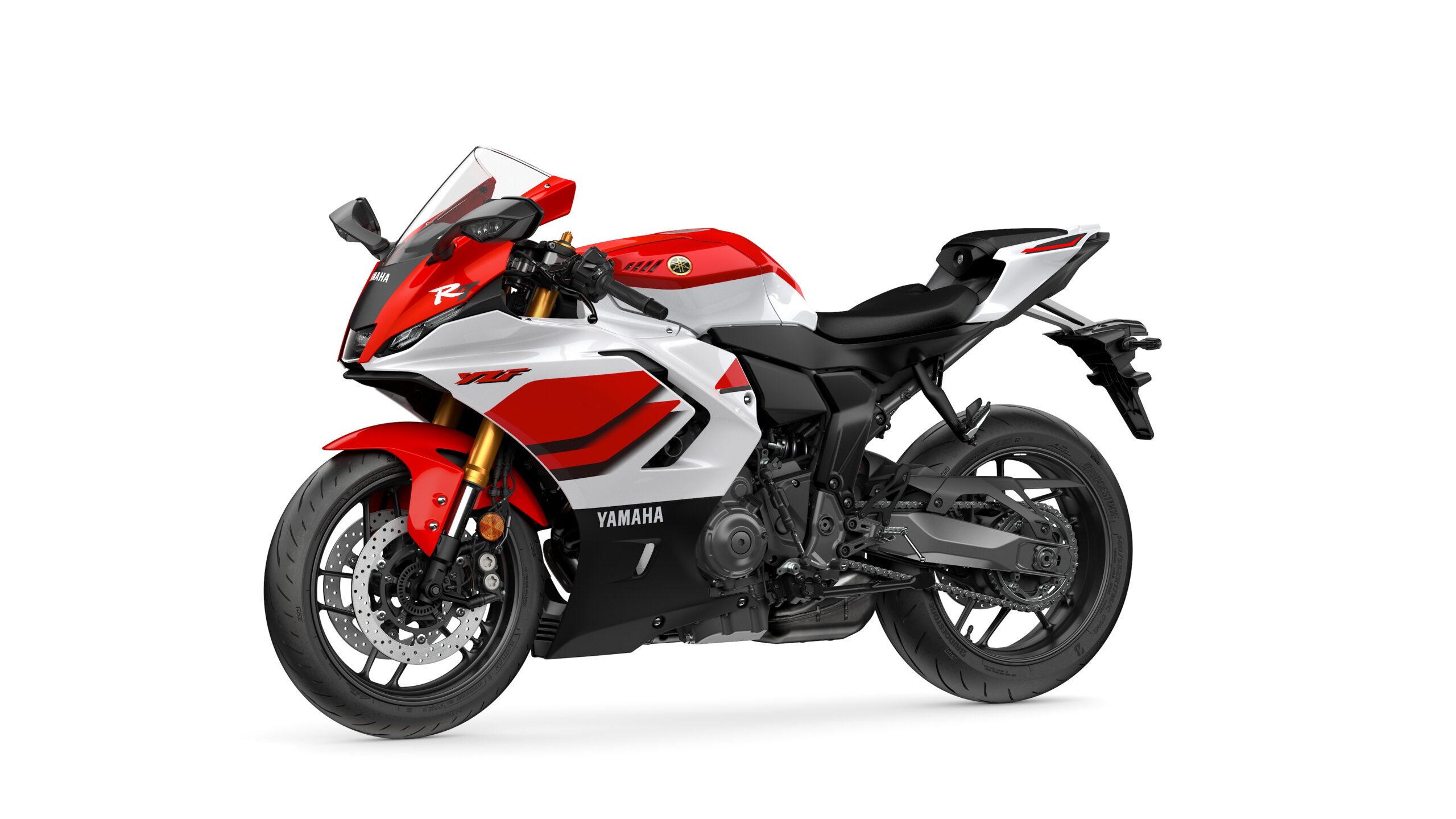 2026 Yamaha R7 Anniversary Edition Lateral Left A red and white Yamaha YZF-R1 motorcycle is displayed at an angle, showcasing its sporty design, aerodynamic features, and modern styling, set against a white background.