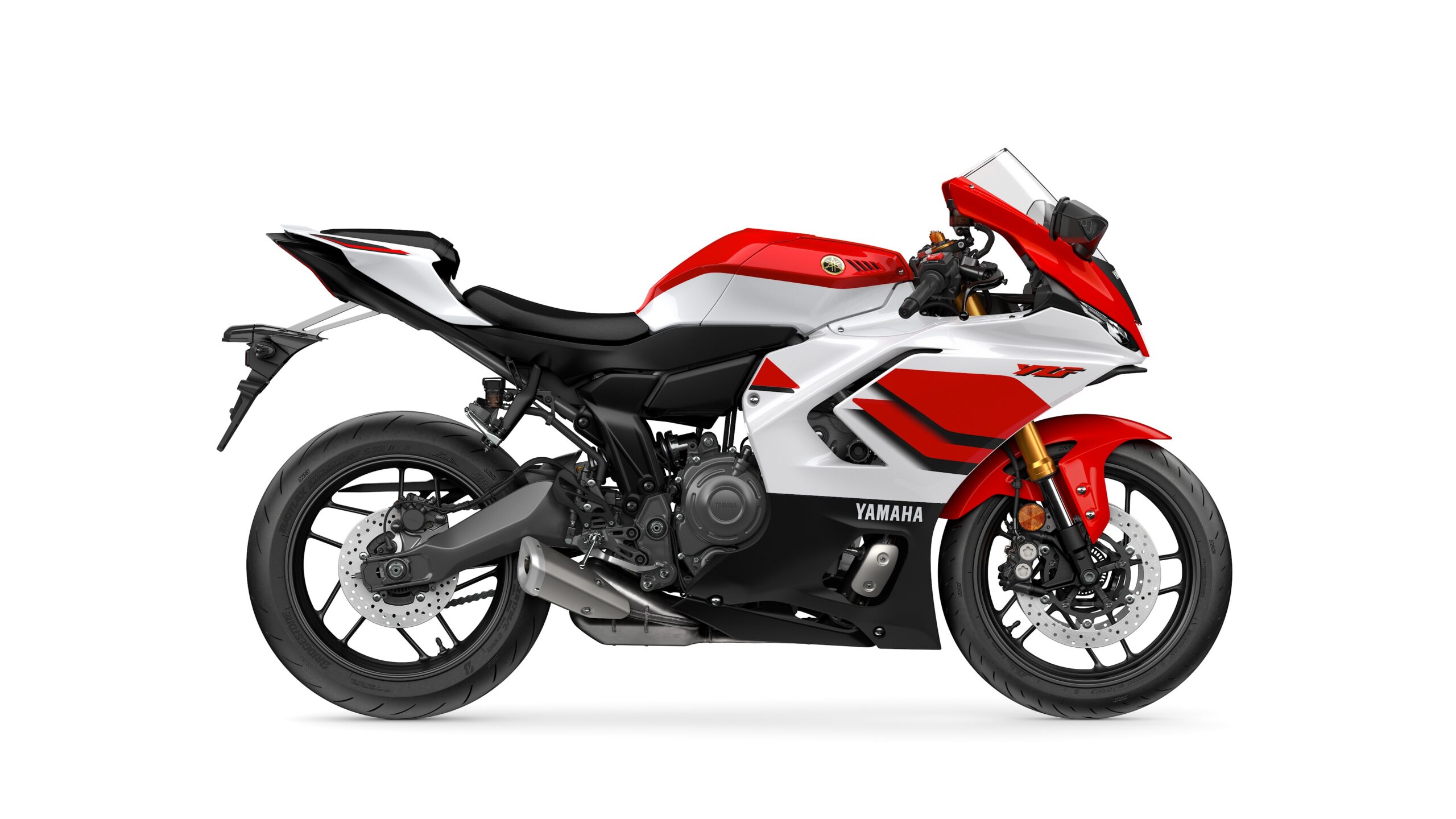 2026 Yamaha R7 Anniversary Edition Right A red and white Yamaha motorcycle, model YZF, is displayed from a side angle, showcasing its sleek design, sporty stance, and advanced features.