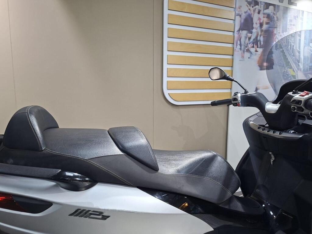 Piaggio MP3 500 2016 7 A close-up view of a modern scooter's seat and handlebars, set against a neutral wall with a patterned background.