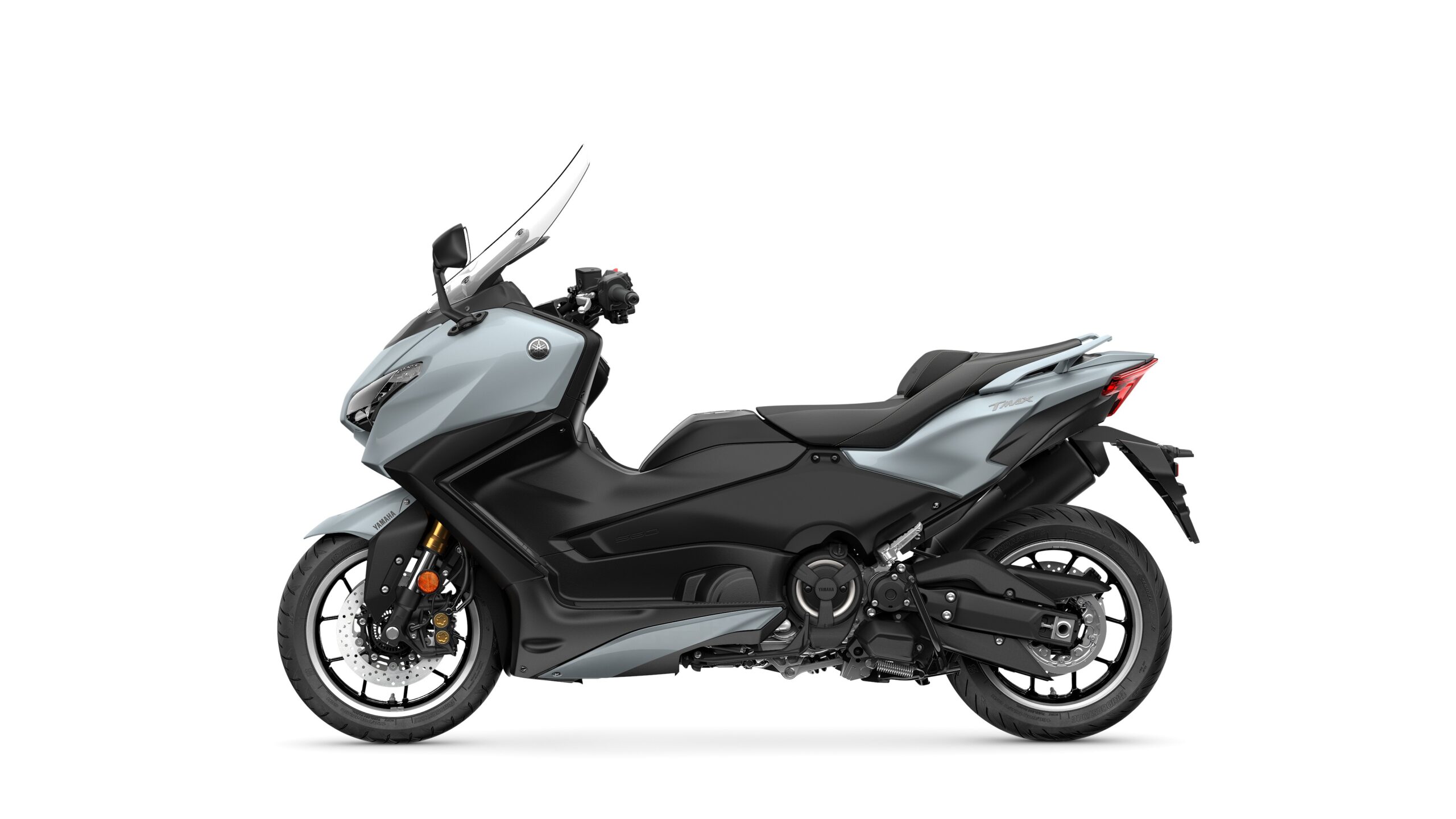 2026 Yamaha TMAX TECH MAX Ceramic Grey Left A sleek, modern motorcycle with a silver and black color scheme, featuring streamlined bodywork, a windscreen, and a sporty rear design, positioned against a white background.