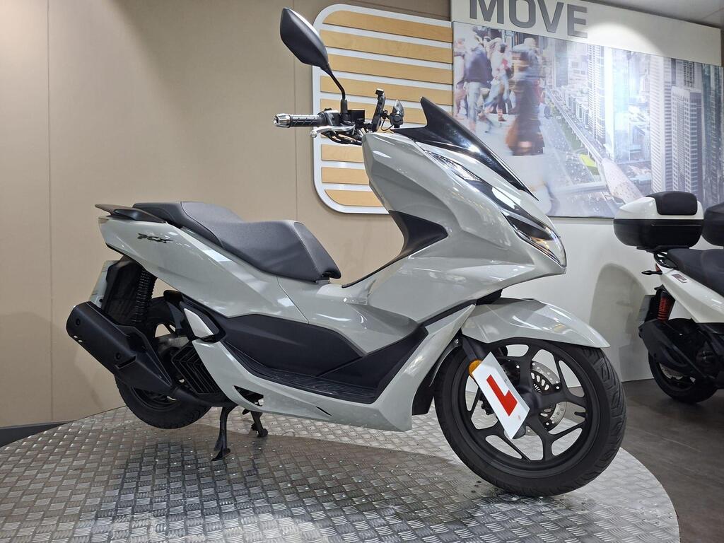 Honda PCX 125 2024 26 A sleek gray scooter with a modern design displayed against a neutral backdrop, featuring a learner's permit tag and a chrome handlebar.