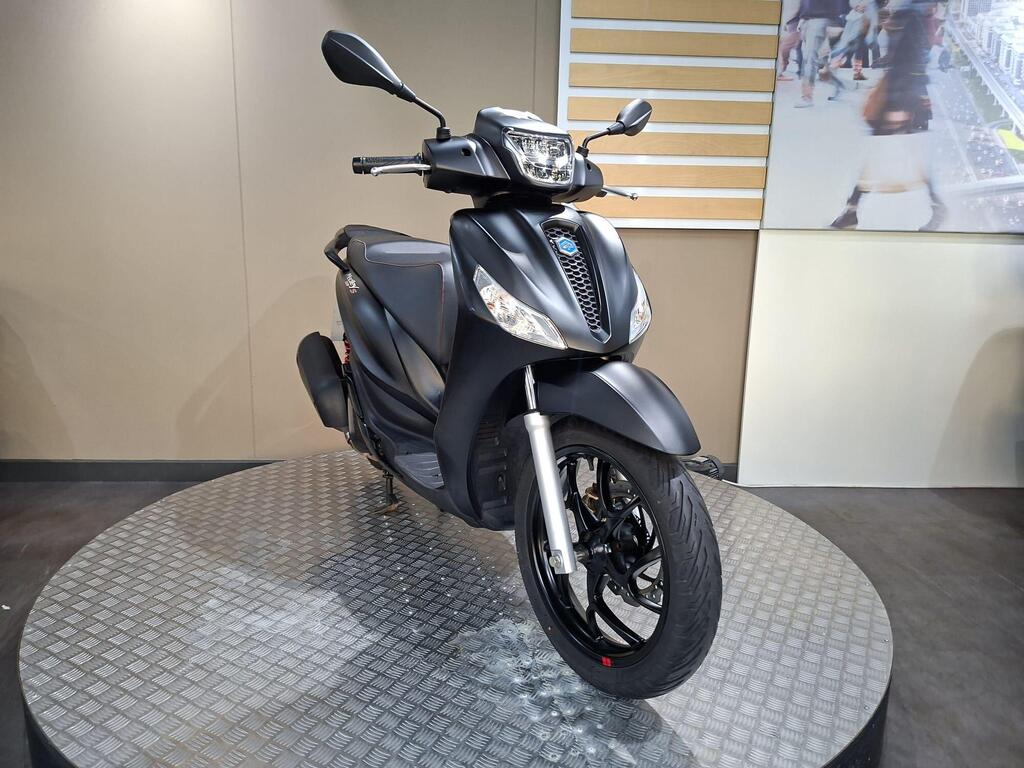 Piaggio Medley (2022) 25 A sleek black scooter displayed on a round, textured platform against a neutral background.