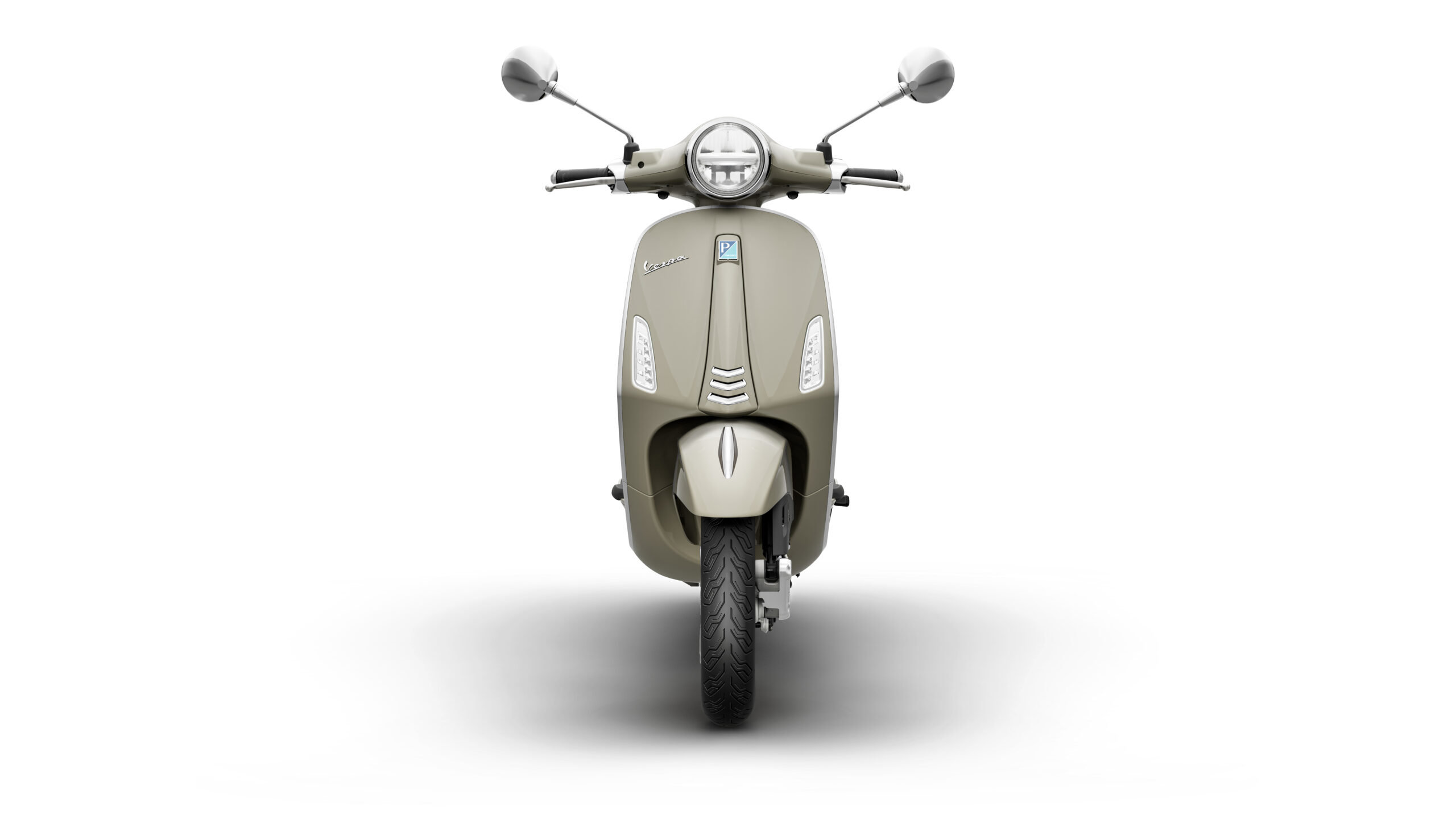 Primavera 125 2026 Beige Avvolgente Front A frontal view of a beige scooter with a rounded headlight and sleek body design, mounted on a single tire. The background is plain white, highlighting the scooter's features.