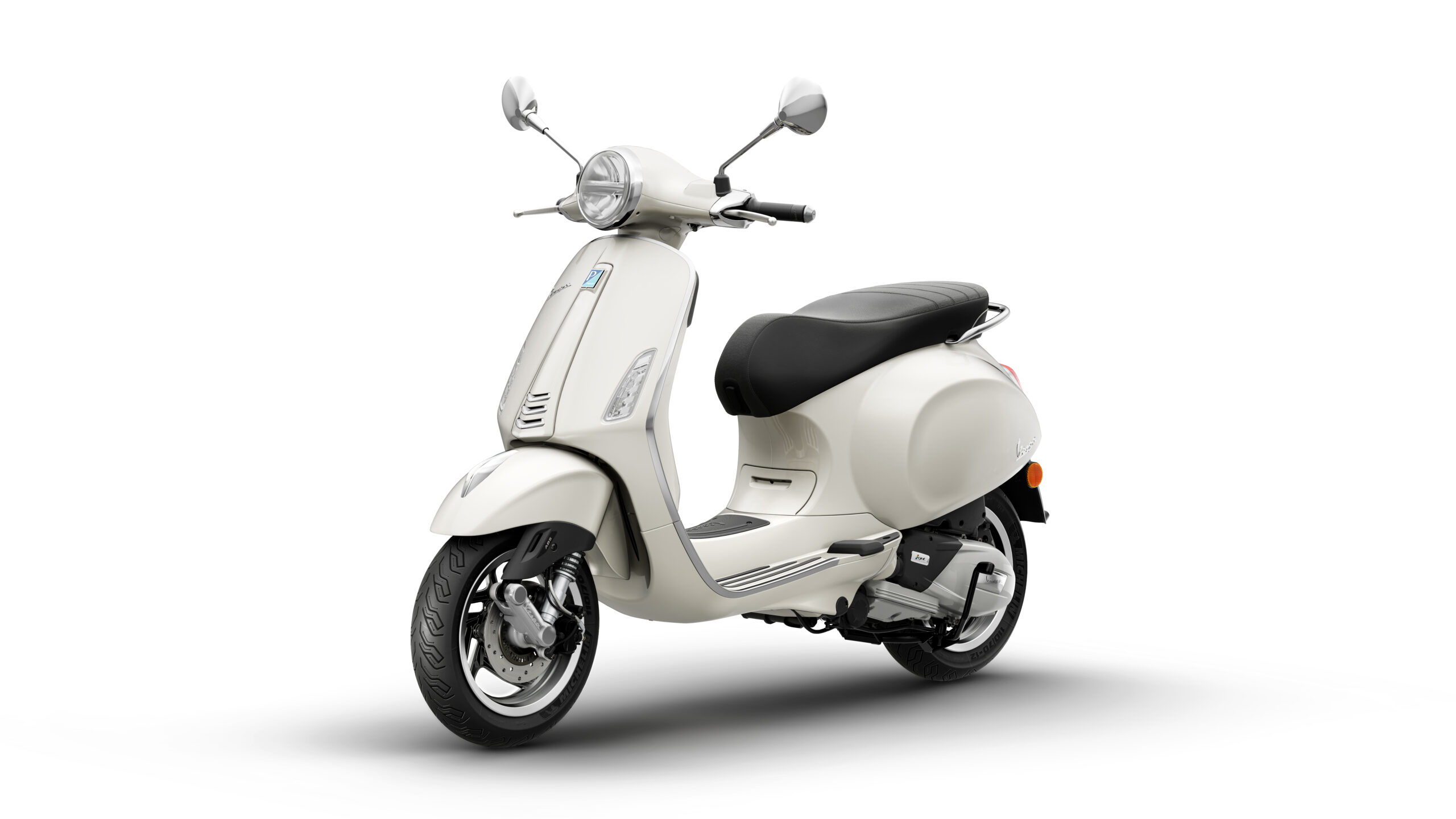 Primavera 125 2026 Bianco Innocente Lateral Left A sleek, white scooter with a retro design, featuring a round headlight, black seat, and chrome accents, positioned on a clean white background.