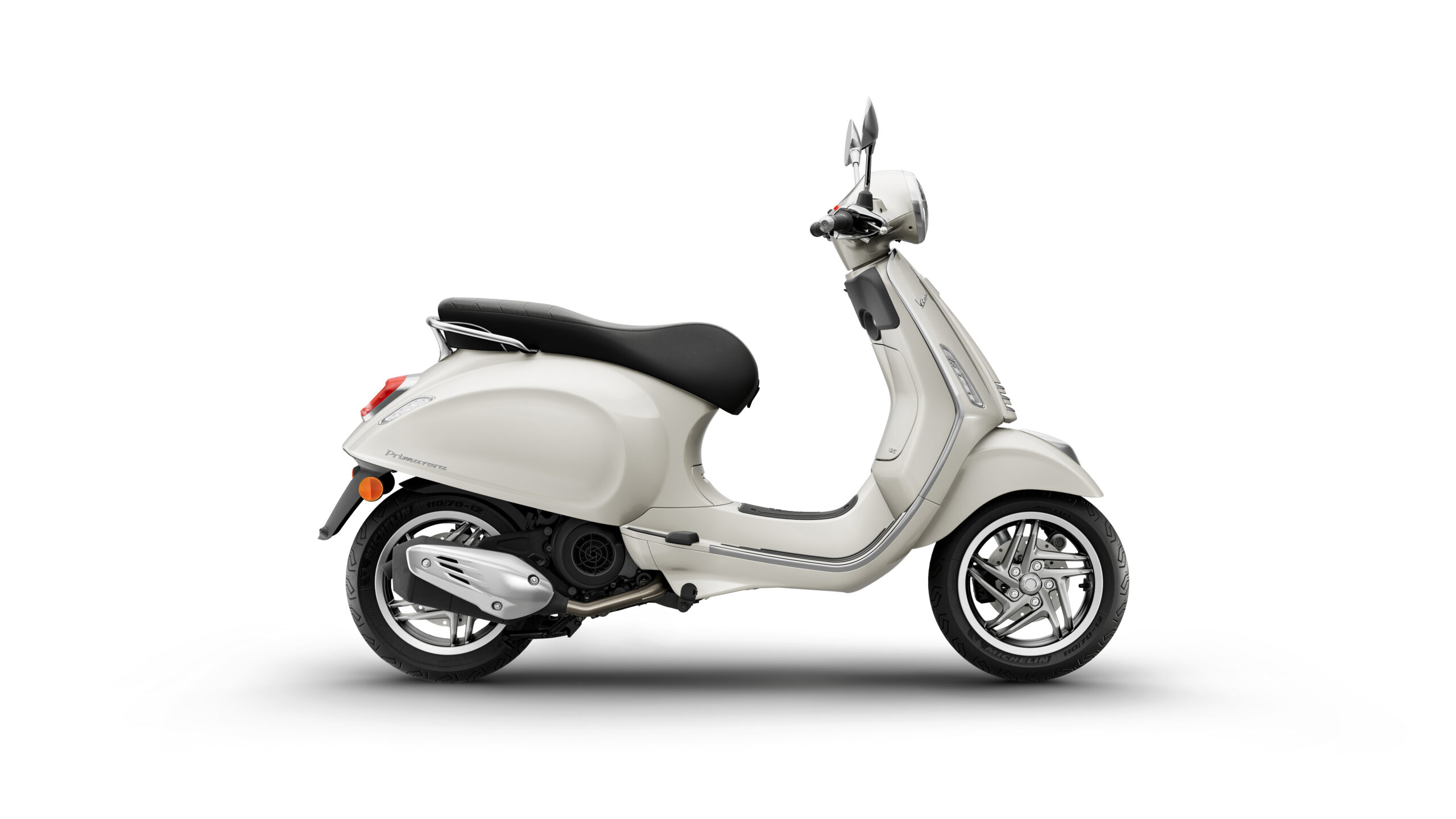 Primavera 125 2026 Bianco Innocente Right A cream-colored scooter with a black seat, viewed from the side, featuring a chrome exhaust and stylish alloy wheels against a white background.