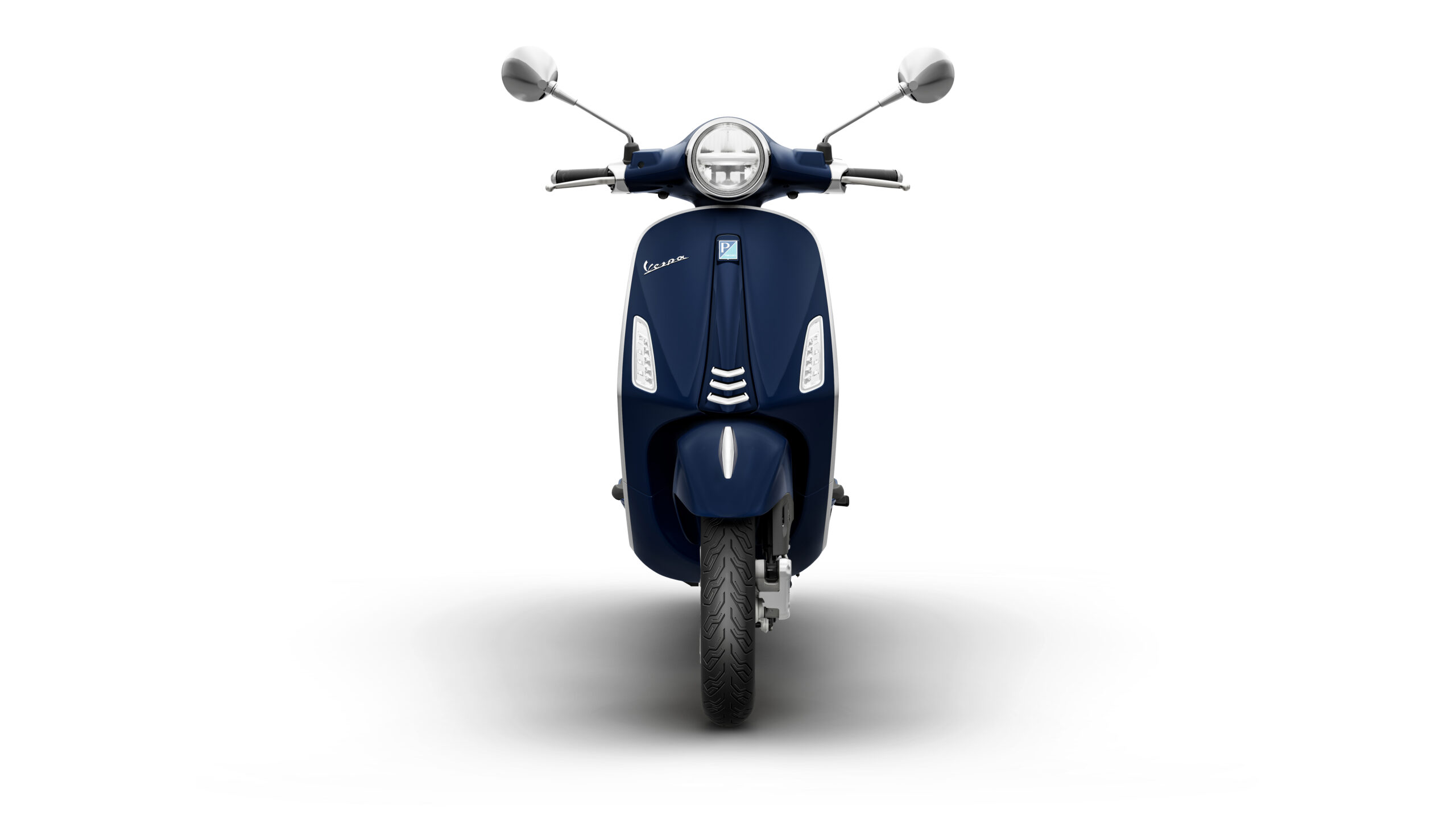 Primavera 125 2026 Blu Energico Front A navy blue scooter is displayed from the front, featuring a round headlight, chrome mirrors, and a sleek design. The background is white, emphasizing the scooter's details.