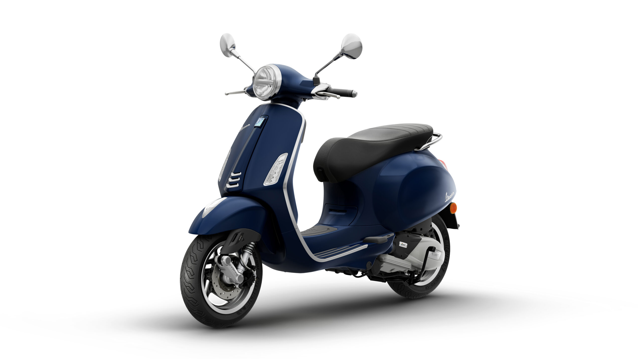Primavera 125 2026 Blu Energico Lateral Left A sleek navy blue scooter with a retro design, featuring a rounded front, chrome accents, and a comfortable black seat, positioned at an angle with a white background.