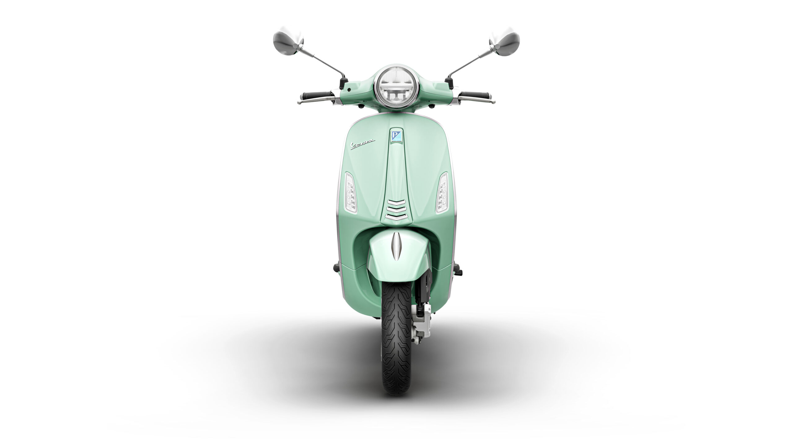 Primavera 125 2026 Verde Amabile Front A front view of a mint green scooter against a white background, showcasing its sleek design, circular headlight, and handlebars with mirrors.