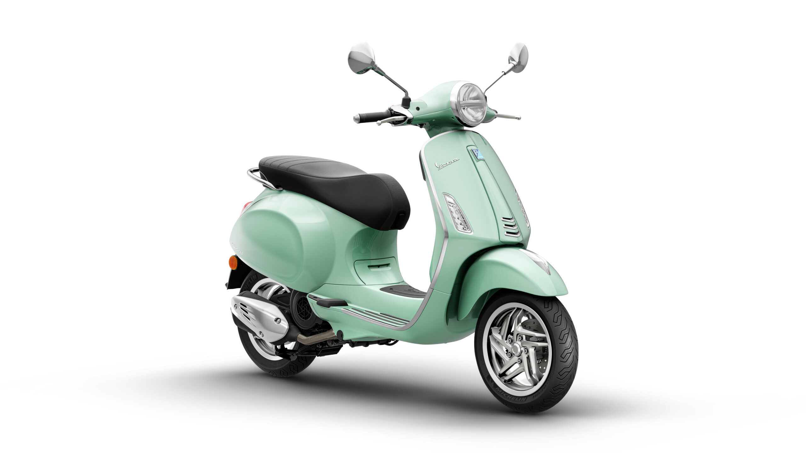 Primavera 125 2026 Verde Amabile Lateral Right A vintage-style mint green scooter with a black seat, chrome mirrors, and a rounded headlight, positioned at a slight angle against a white background.
