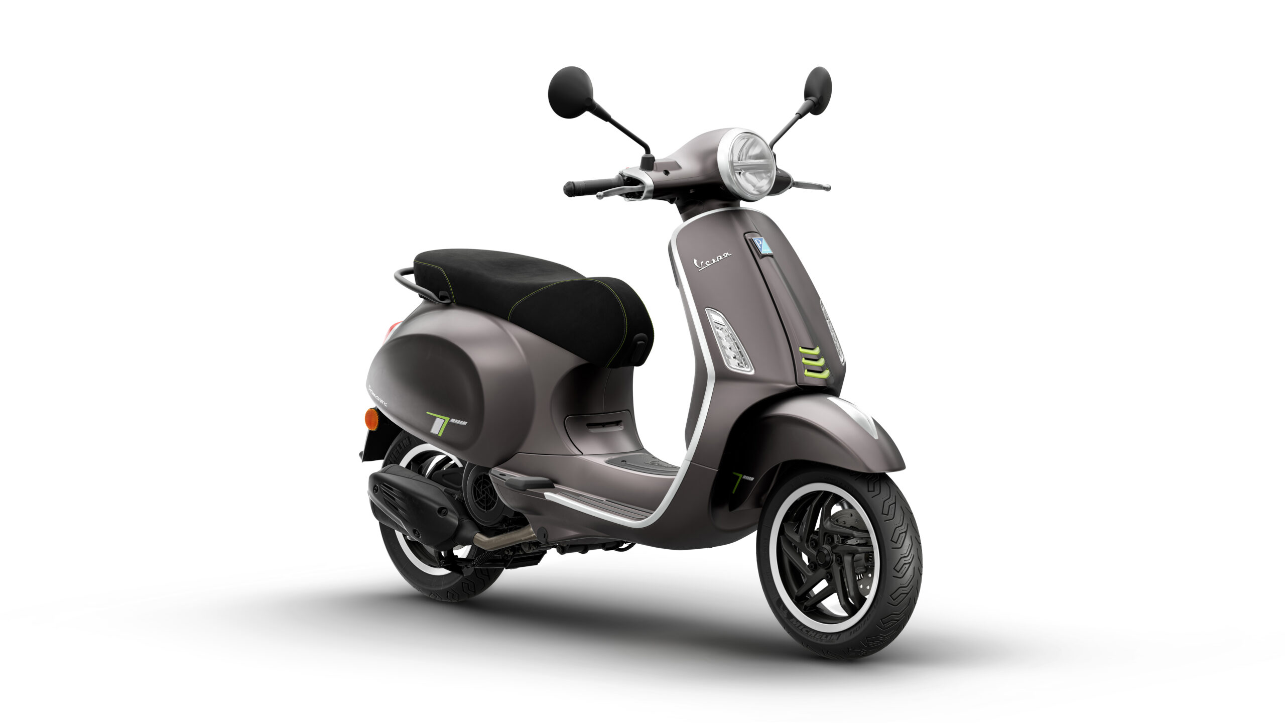 Primavera Tech 125 2026 Grigio Ottimista Lateral Right A stylish gray scooter with a black seat and green accents is displayed at an angle, showcasing its iconic design and chrome details.