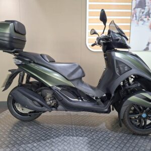 Piaggio MP3 300 Yourban LT 2018 A sleek black and green scooter displayed on a patterned surface, featuring a top case for storage, showcasing its modern design and dual front wheels for stability.