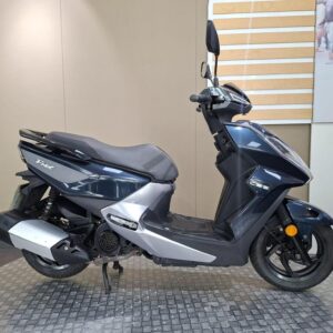 SYM FNX 125 2020 A sleek blue and silver scooter parked on a textured surface, featuring a comfortable seat, a compact design, and rearview mirrors.