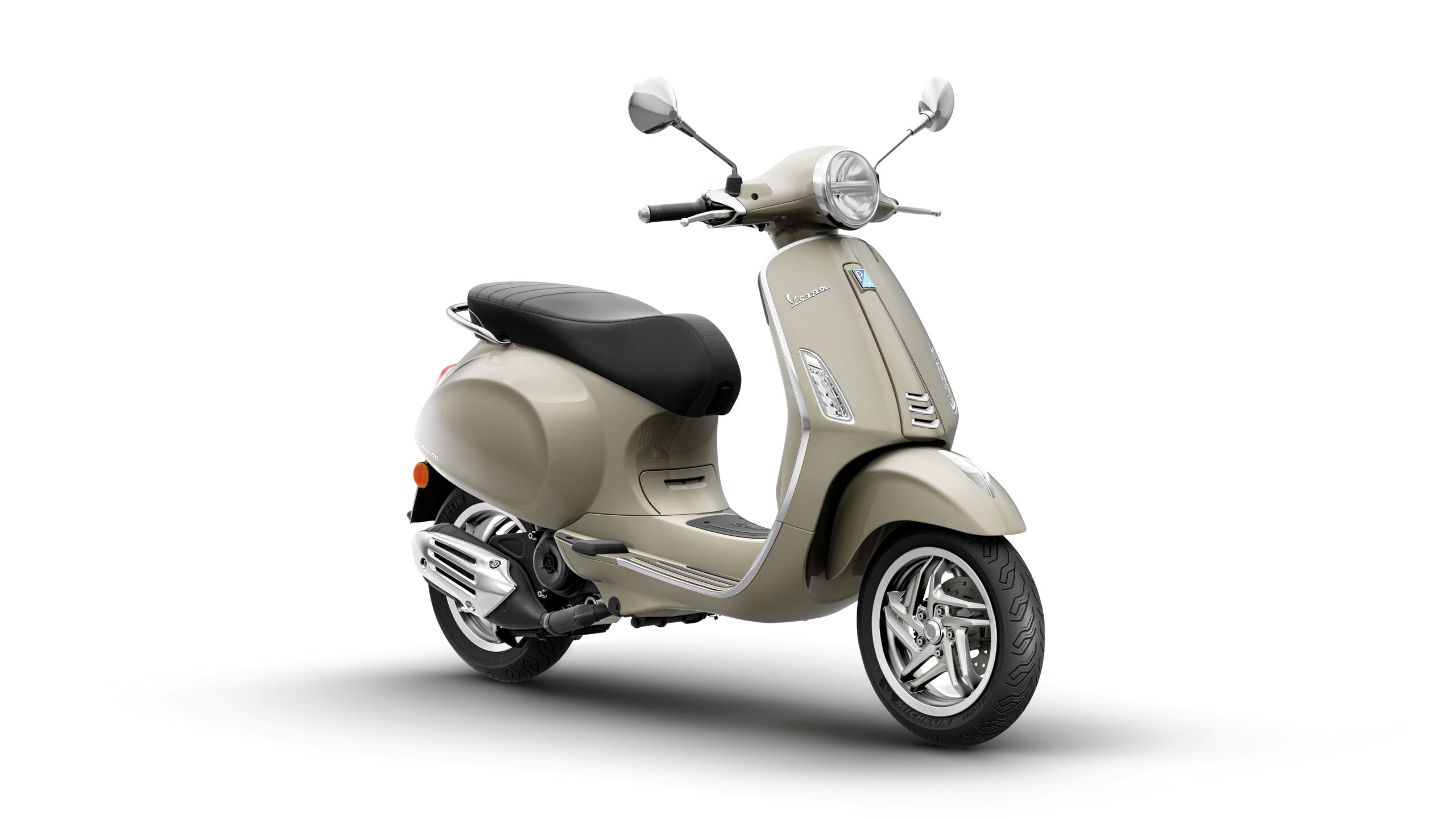 Vespa Primavera 50 MY26 Beige Avvolgente Lateral Right A beige scooter with a sleek design, featuring a black seat, chrome accents, and a rounded headlight, set against a white background.