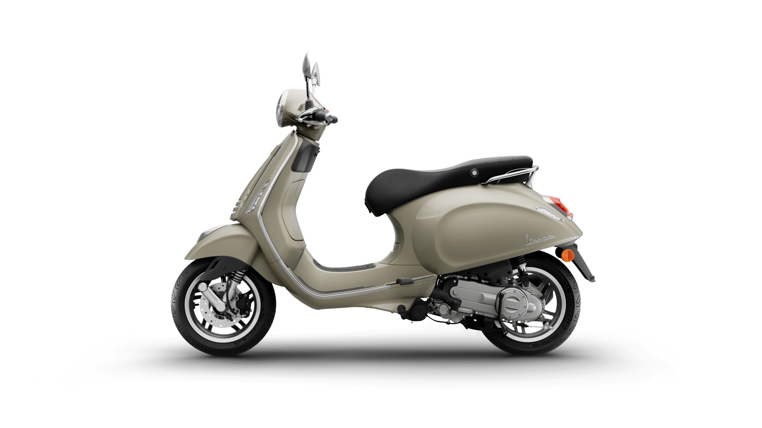 Vespa Primavera 50 MY26 Beige Avvolgente Left A beige scooter in profile view, featuring a rounded body, black seat, and chrome accents, set against a white background.