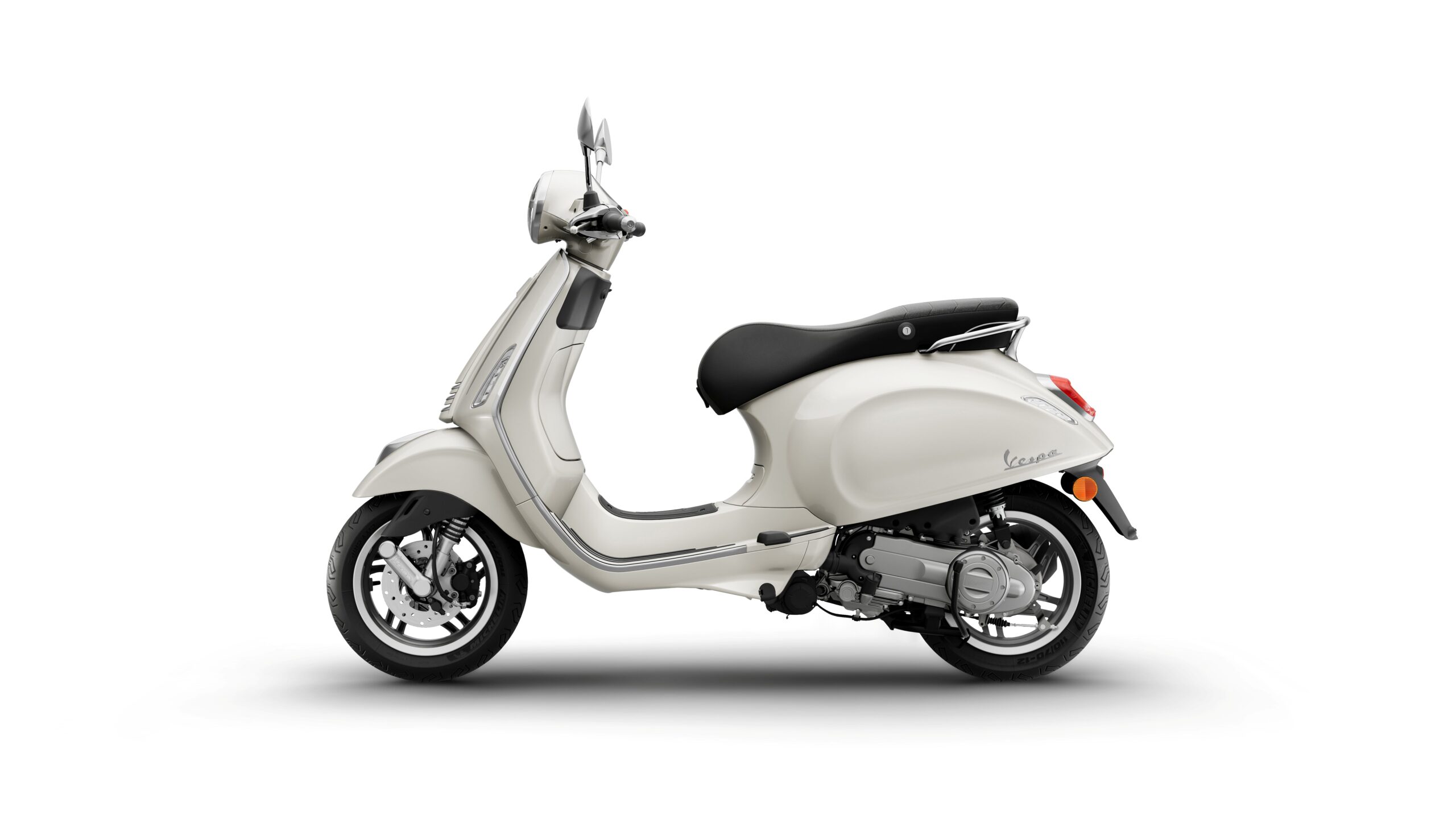 Vespa Primavera 50 MY26 Bianco Innocente Left A side view of a cream-colored Vespa scooter with a black seat parked on a white background.