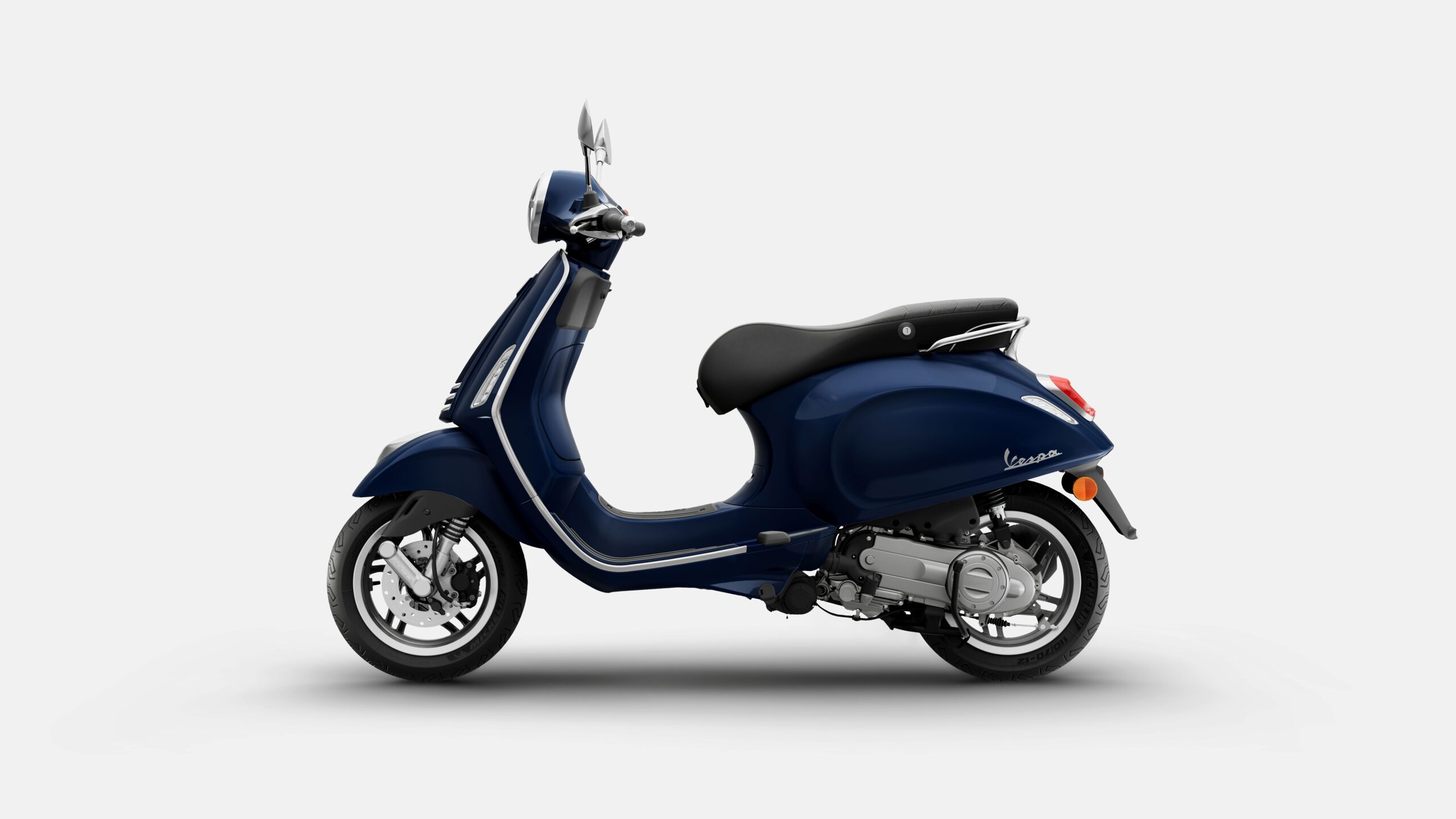 Vespa Primavera 50 MY26 Blue Energico Left A navy blue Vespa scooter displayed from the side, featuring a sleek design, chrome accents, and a comfortable black seat.