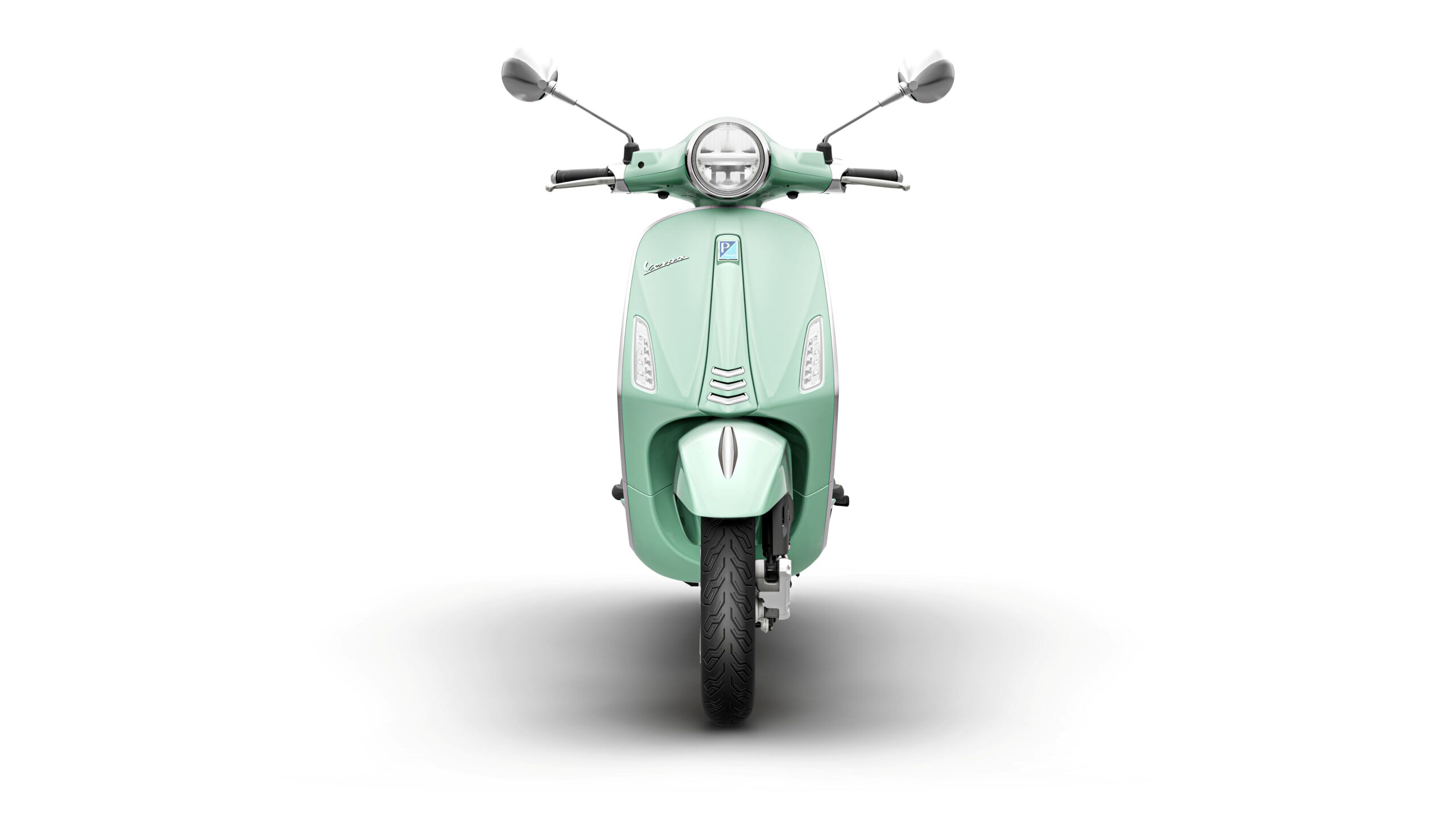 Vespa Primavera 50 MY26 Verde Amabile Front A front view of a mint green scooter with a vintage design, showcasing its round headlight, mirrors, and a sleek body.