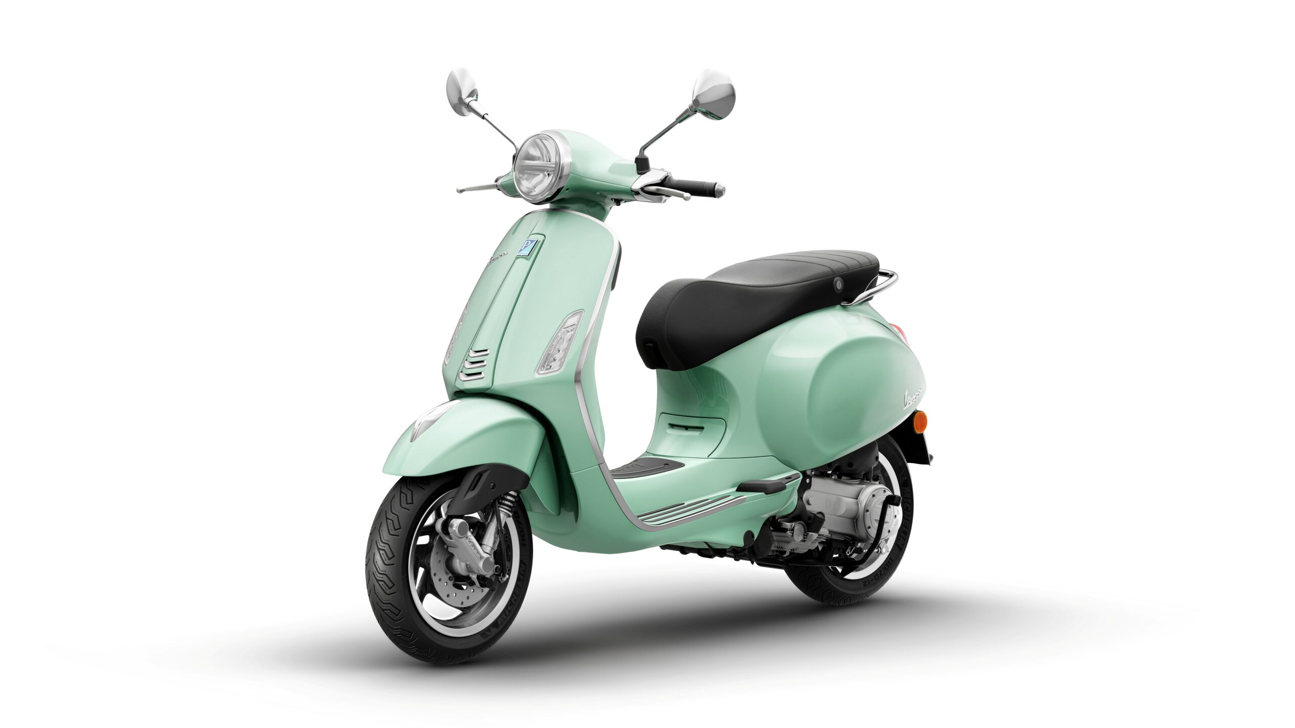 Vespa Primavera 50 MY26 Verde Amabile Lateral Left A mint green scooter with a retro design, featuring a black seat, chrome details, and a classic headlight, positioned against a white background.