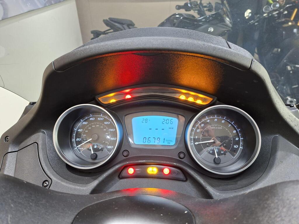 Piaggio MP3 350 LT Sport 2020 13 Dashboard of a motorcycle showing speedometer in km/h, tachometer in RPM, and digital display with mileage and temperature indicators. Warning lights are also visible.