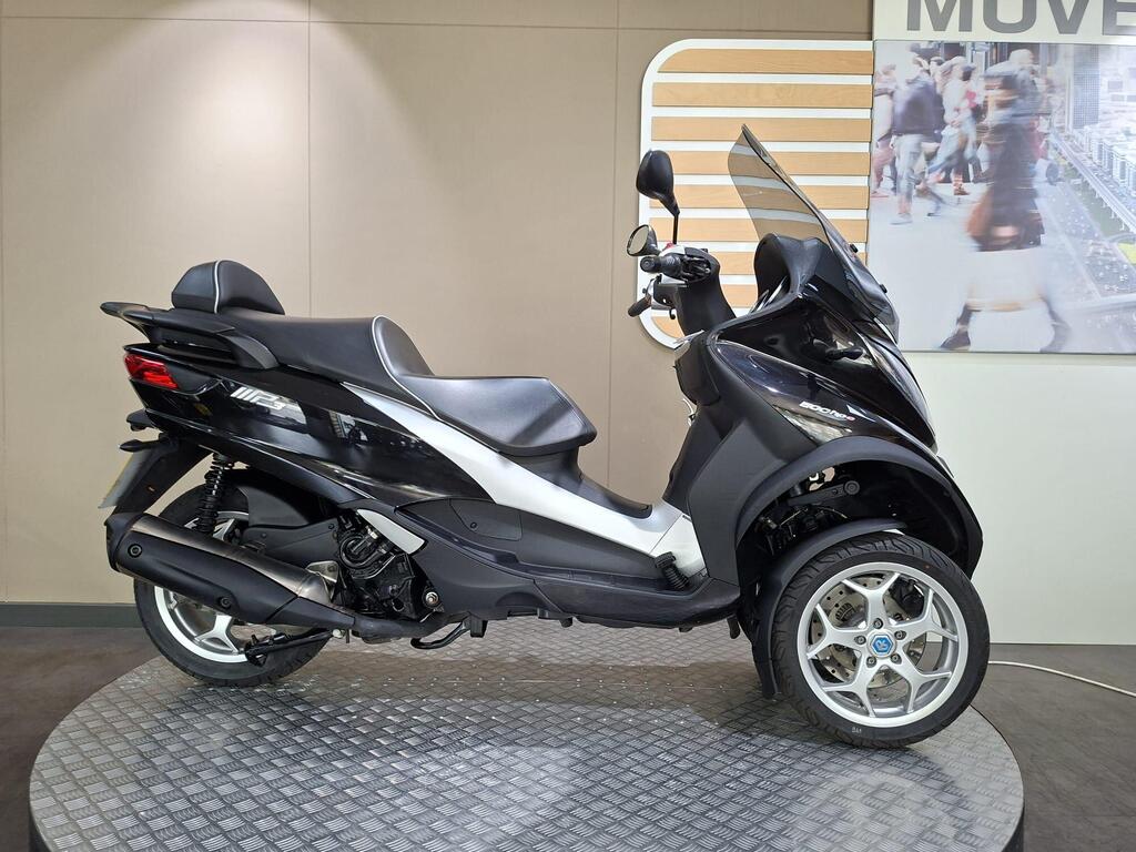Piaggio MP3 500 Business 2021 1 Piaggio MP3 500 Business 2021 A black and silver three-wheeled scooter displayed on a checkered platform against a neutral background.