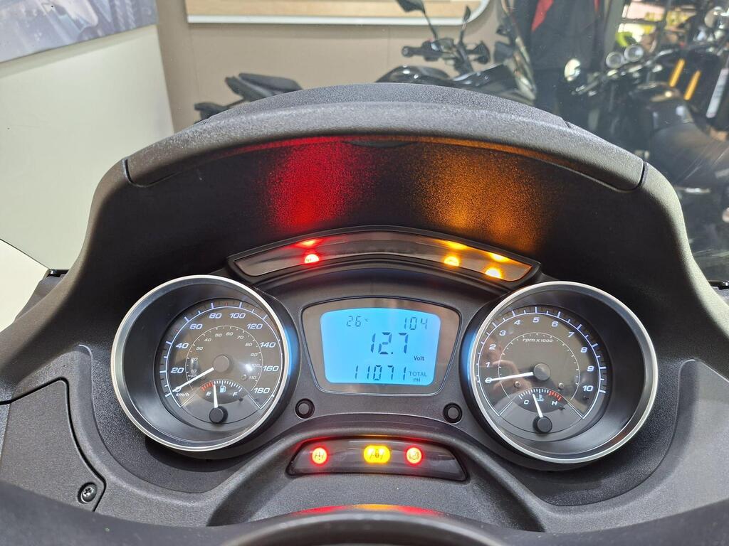 Piaggio MP3 500 Business 2021 13 Dashboard of a scooter displaying speedometer, odometer, and warning lights. The speedometer shows a speed of 26 km/h, the odometer reads 1,107 miles, and the digital display shows a voltage of 12.1.