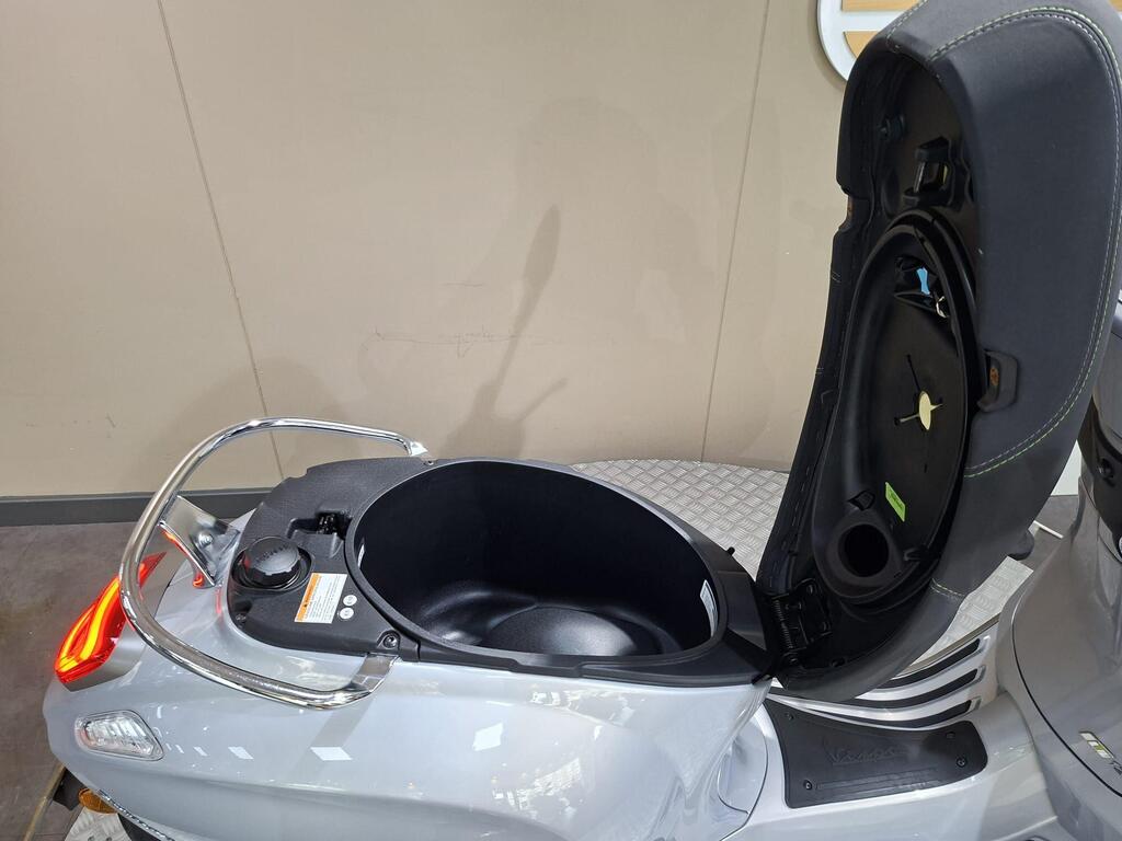 Vespa Primavera 125 2025 11 An open storage compartment on a gray scooter, with visible interior space and a circular cap, set against a neutral background.