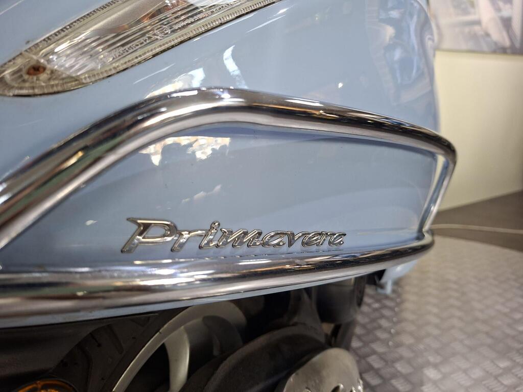 Vespa Primavera 50 2017 10 Close-up of a light blue scooter showcasing the chrome badge that reads "Primavera" on its side panel.