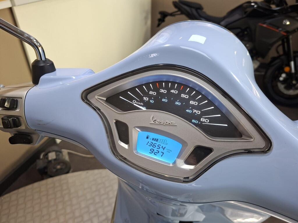 Vespa Primavera 50 2017 16 Close-up view of the speedometer and dashboard of a light blue Vespa scooter, displaying a speedometer, odometer reading of 13,654 km, and a fuel gauge showing 92%.
